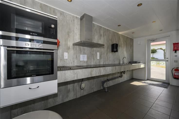 Inredning av ett kökspart med trägolv och träpaneler, köksbänk, skåp och hushållsapparater i trä och metall hos Gröndals Camping & Stugor.