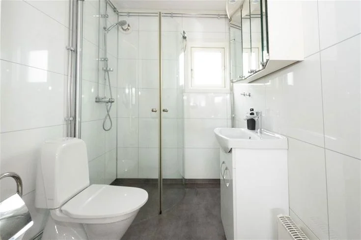 Ett badrum på Gröndals Camping & Stugor med ett toalettstol, handfat och kaklade väggar samt golv.