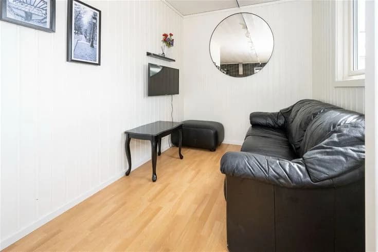 En mysig stuga med trädetaljer på Gröndals camping & stugor, inredd med en soffa och trägolv i ett ljust vardagsrum.