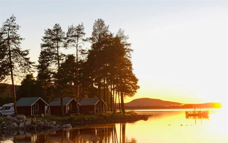 En stilla sjö i skymningsljus med vackra reflektioner av den färgsprakande solnedgången över vattenytan vid Camp Viking.