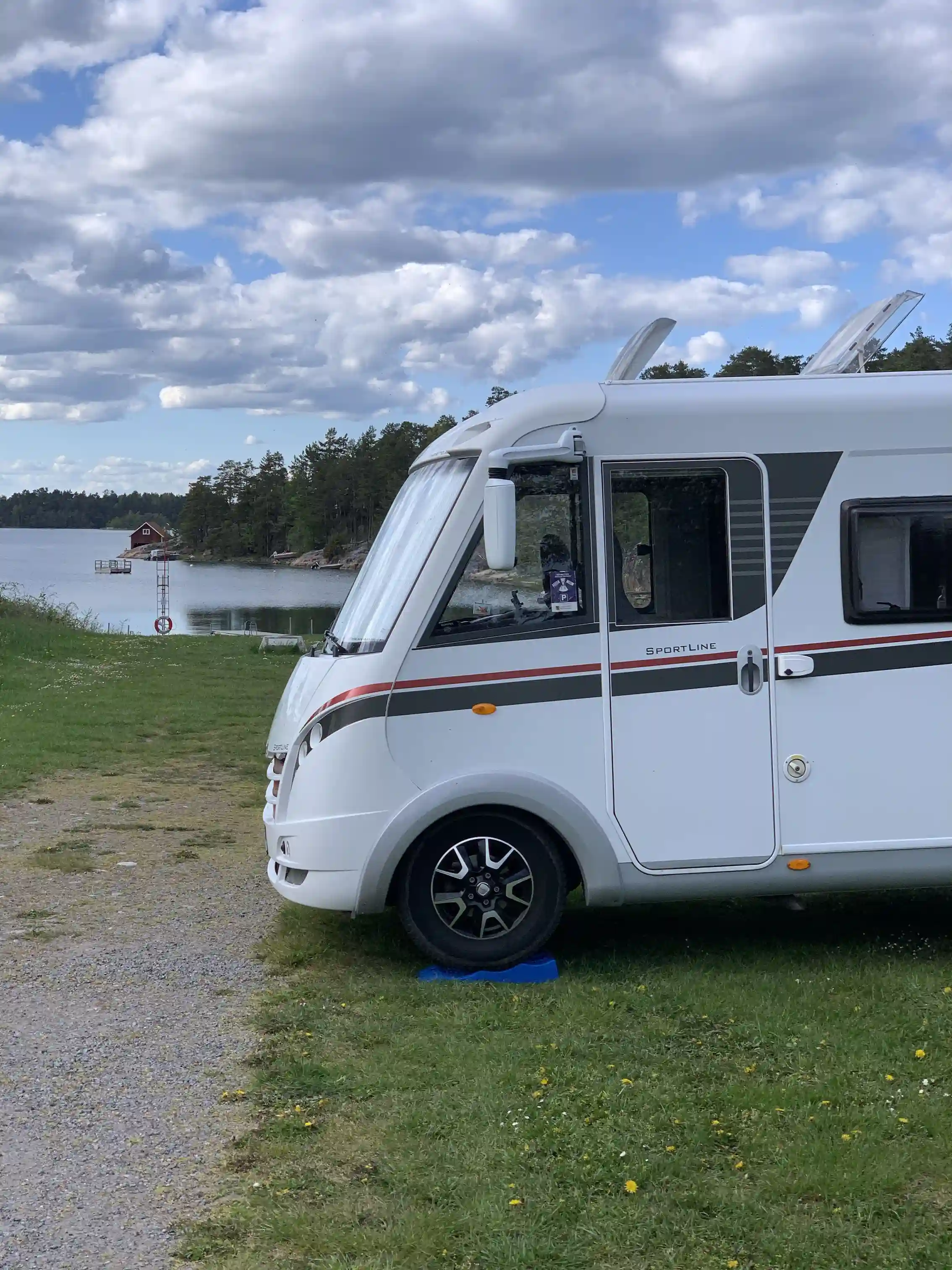 En husvagn med en tillkopplad bil står parkerad på Tyrislöt camping, omgiven av gröna träd och cyklar vid sidan. Atmosfären är lugn och avkopplande, idealisk för campingliv.
