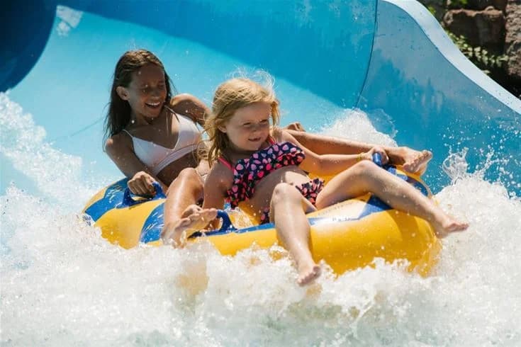 En solig sommardag på Kneippbyn Resort Visby, med glada besökare som njuter av vattenparken och fritidsaktiviteter utomhus.