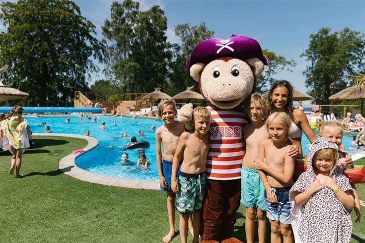 En solig sommardag på Kneippbyn Resort Visby, barn leker och har roligt i en stor vattenpark med pool. Perfekt för semester och nöje med familjen.