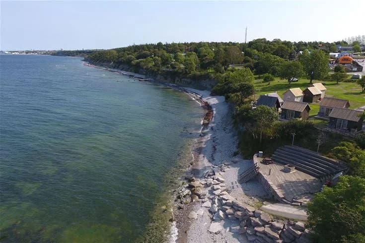 En strand med vatten och sand vid Kneippbyn Resort Visby en solig sommardag.