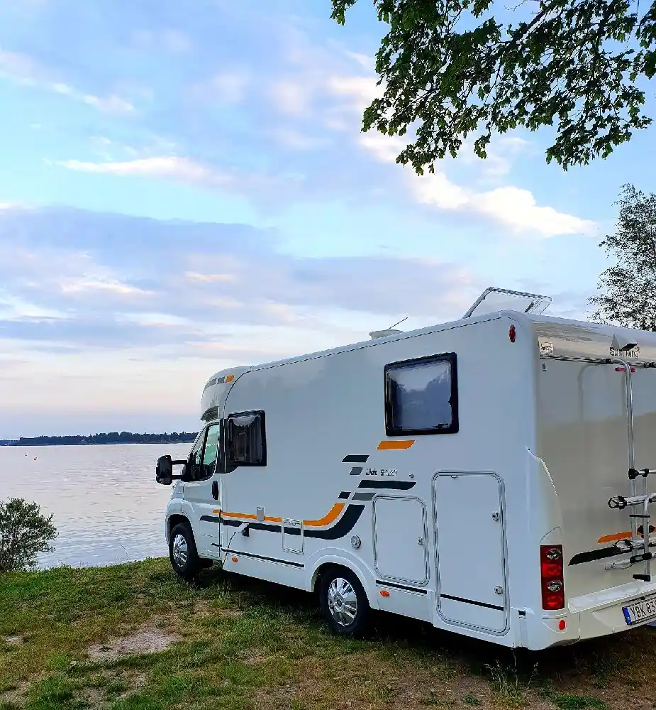 En husbil parkerad vid Gräsöbadens familjecamping, omgiven av grönska och skog.