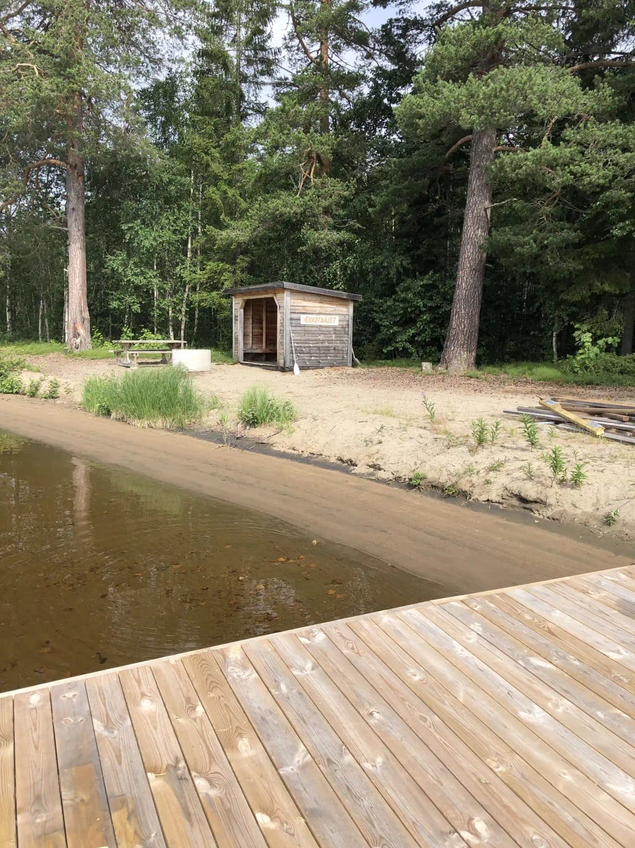En trästuga vid vattnet på Rätans camping, omgiven av en träbrygga.
