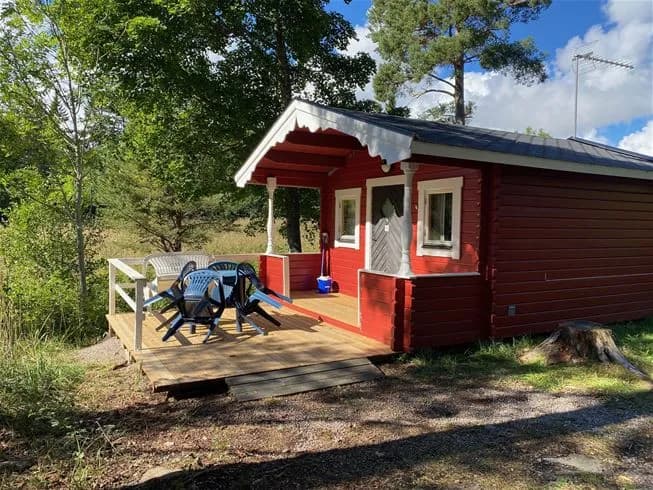 En trästuga i lantlig miljö vid Ängskärs havscamping, med en enkel dörr och omgivande timmerdetaljer.