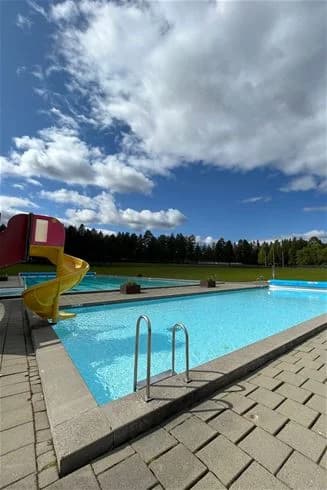 En inbjudande pool på Strömsunds camping omgiven av gröna områden, där besökare njuter av fritidsaktiviteter och semester i en avslappnad atmosfär.