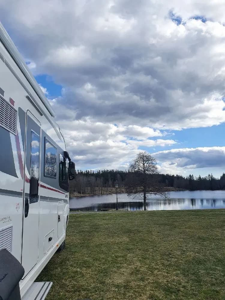 En husvagn och mobilhem står parkerade på gräsmattan vid Påarps gård i skymningen.