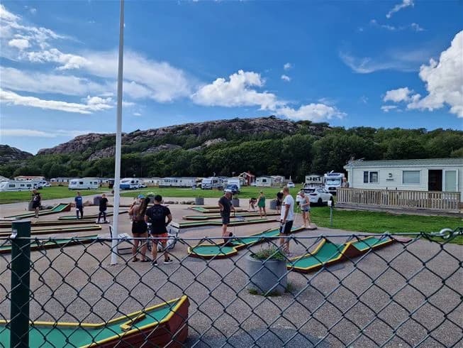 Campingplats med tält under presenningar, omgiven av grönska. Perfekt för rekreation och semester vid Siviks camping.