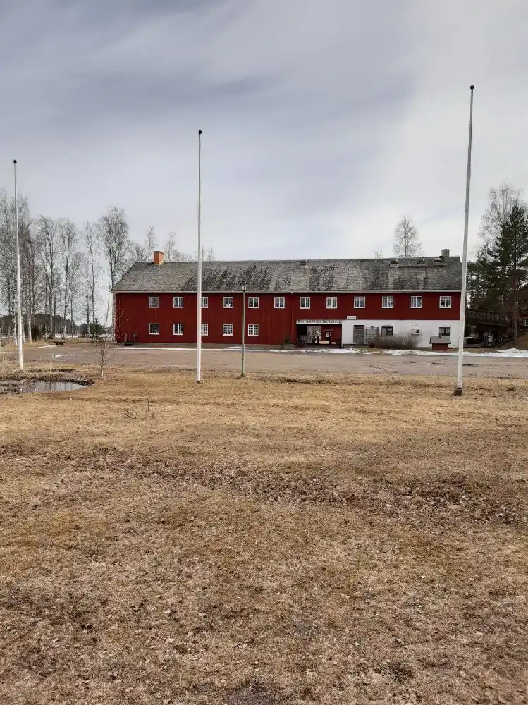 En historisk byggnad på Brunskog hembygdsgård, omgiven av grönskande landskap och öppna fält.