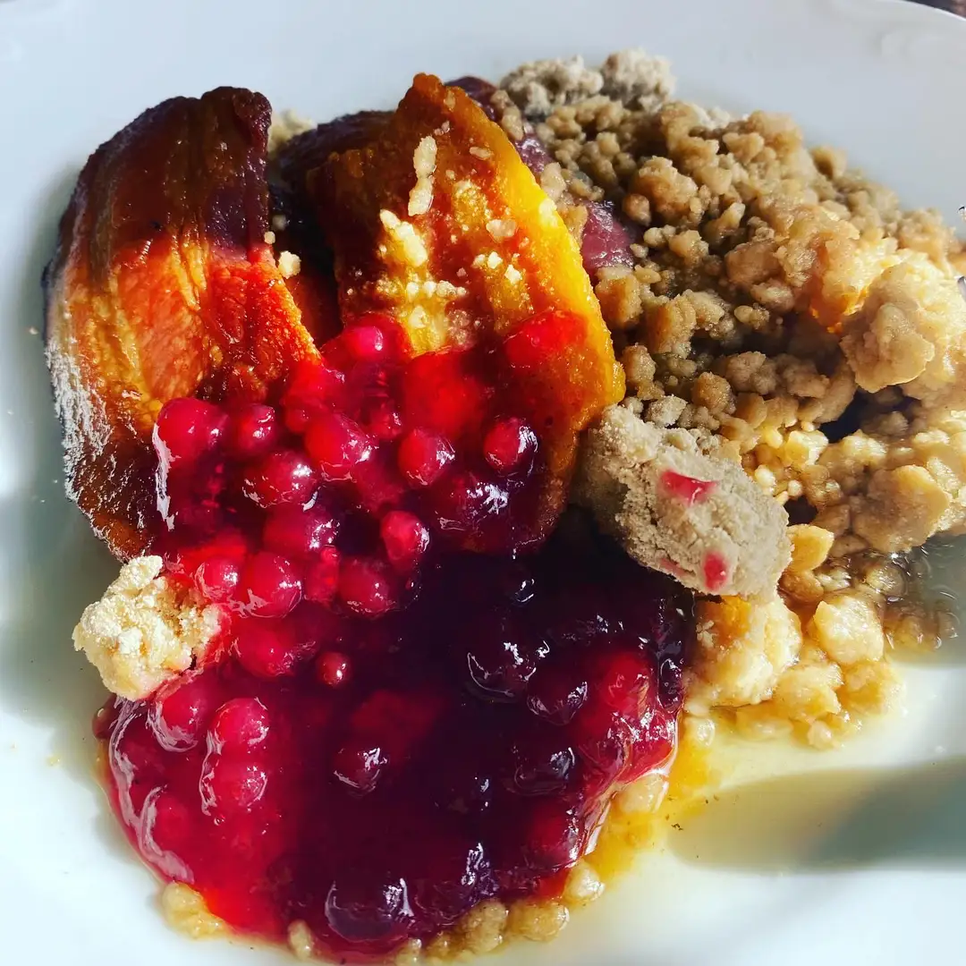 En bild av ett träbord dukat med frukosttillbehör på Gräsmarks hembygdsgård. På bordet finns olika maträtter och tillbehör, inklusive lingonsylt, som tillför en traditionell svensk känsla. Tallrikar och bestick kompletterar dukningen.