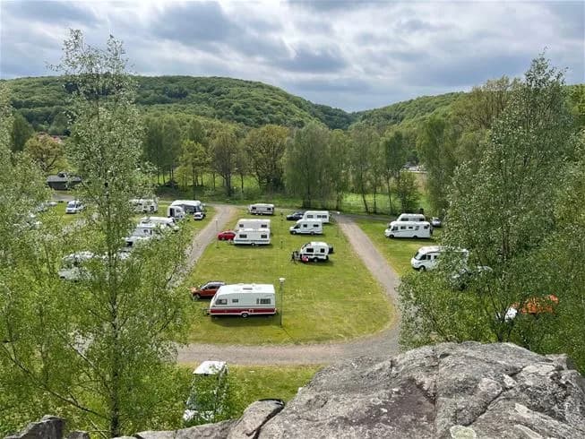 En bild på parkeringen vid Skäralids camping där flera olika typer av fordon, inklusive husbilar och familjebilar, är parkerade.