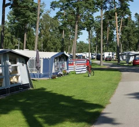En närbild av en cykel parkerad på Ystad Camping, med fokus på cykelns däck och styre.