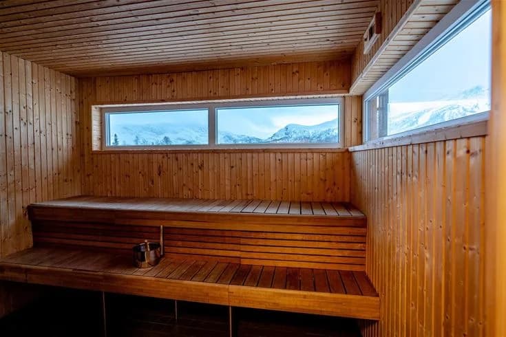En träbeklädd bastu i Camp Kittelfjäll, med dagsljus som strömmar in, träplankor på väggarna och golvet, och ett rustikt, naturligt utseende.