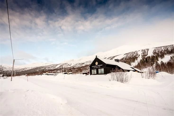 Vy över Kittelfjäll med snötäckta berg och stugor, en populär vintersportdestination i fjällen.