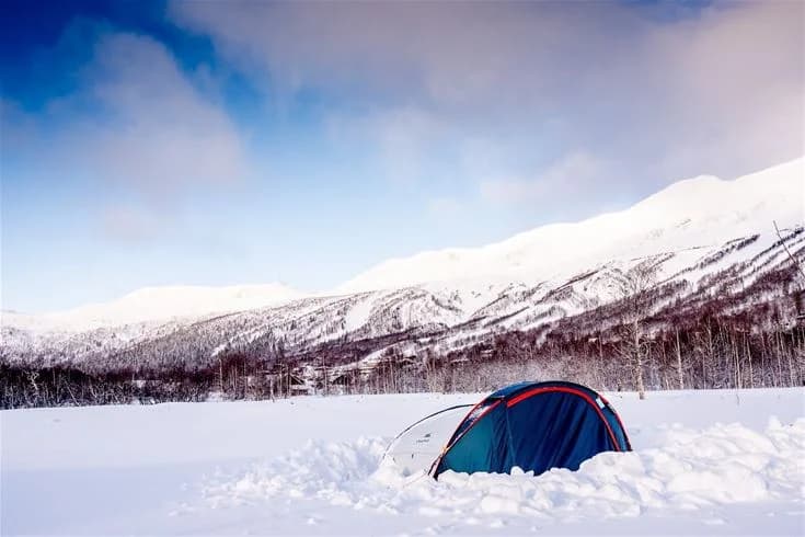 Snöklädda berg i Kittelfjäll under vintertid med en vidsträckt bergskedja i bakgrunden, en populär destination för vinterrekreation och vildmarksupplevelser.