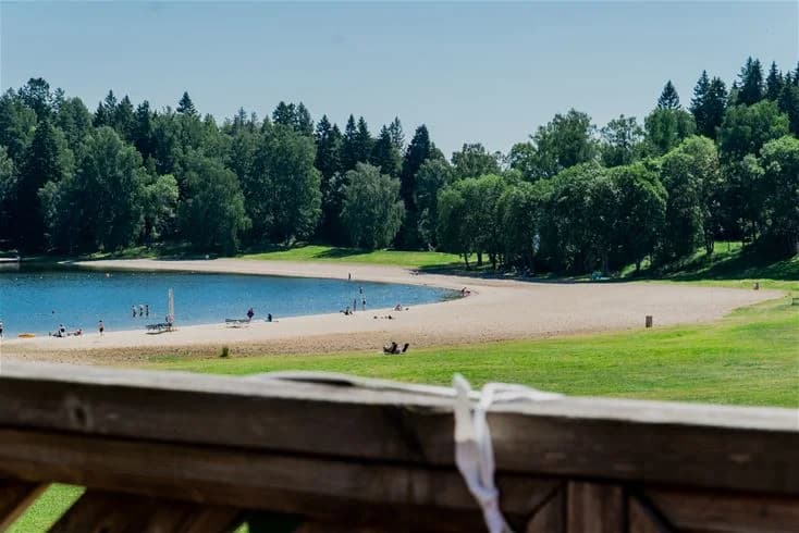 En vacker sjö med en stenig strandlinje omgiven av lummiga träd vid Farstanäs camping & havsbad, perfekt för rekreation och avkoppling.