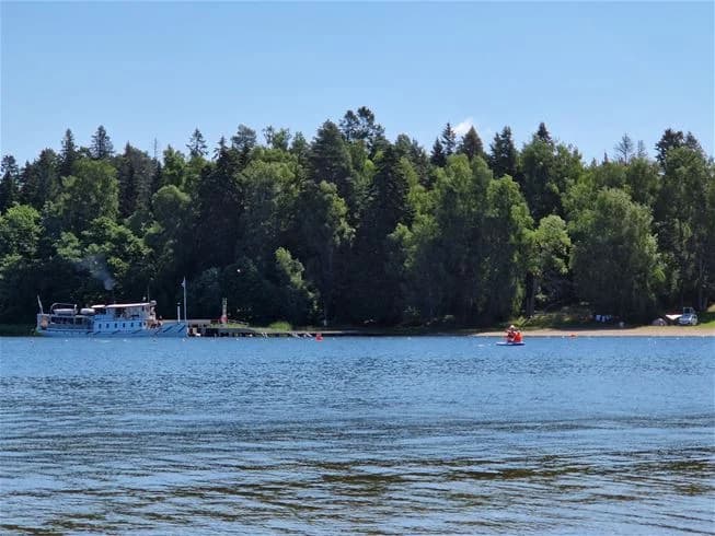 En scen vid Farstanäs camping & havsbad som visar en båt på en vattenled, omgivet av kustlandskap och sjö omgivningar.