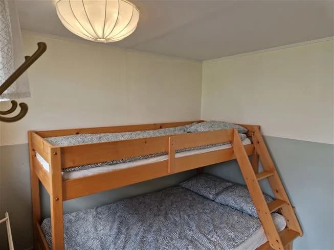 Sovrum med våningssäng och dubbelsäng, träinredning och parkettgolv på Farstanäs camping & havsbad.