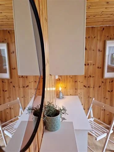 En stilren, träinspirerad interiör med naturliga trätoner. Elegant belysning och spegelreflektioner kompletterar den varma atmosfären. Golv av hårdträ skapar en harmonisk känsla. Perfekt för en avkopplande vistelse på Farstanäs camping & havsbad.