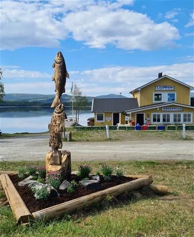 En fångad fisk i närbild vid Jormvattnets fiskecamp, omgiven av vatten och naturskön miljö.