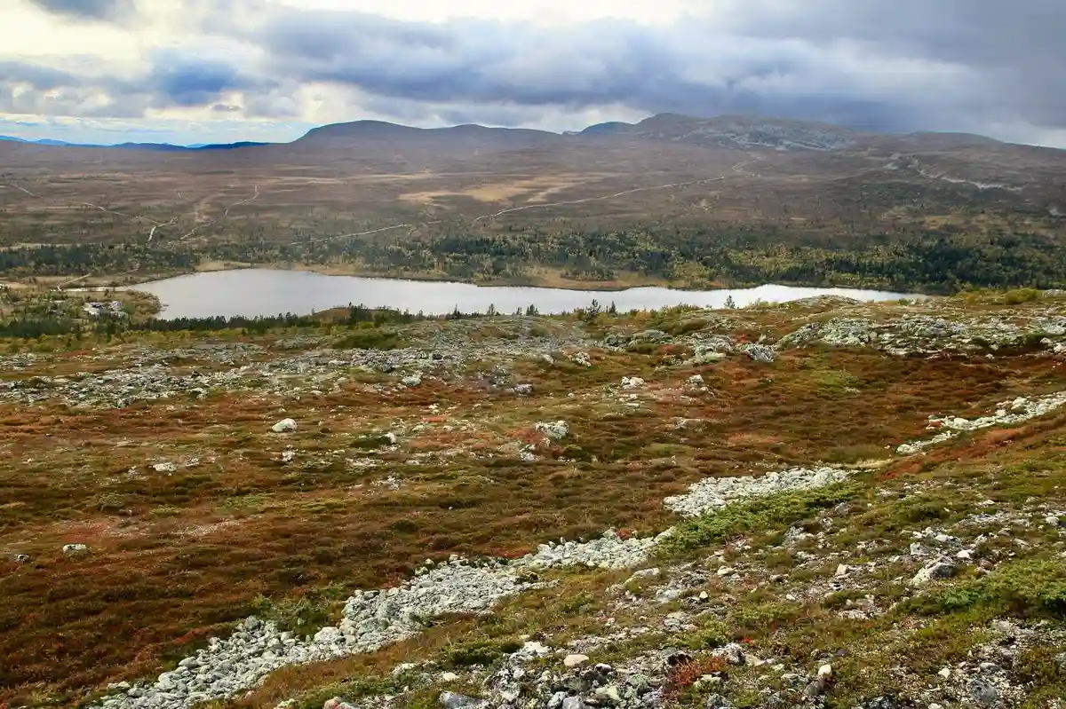 En vidsträckt vy över Idre fjäll camping med omgivande berglandskap och moln, där den orörda naturen skapar en känsla av vildmark och lugn.