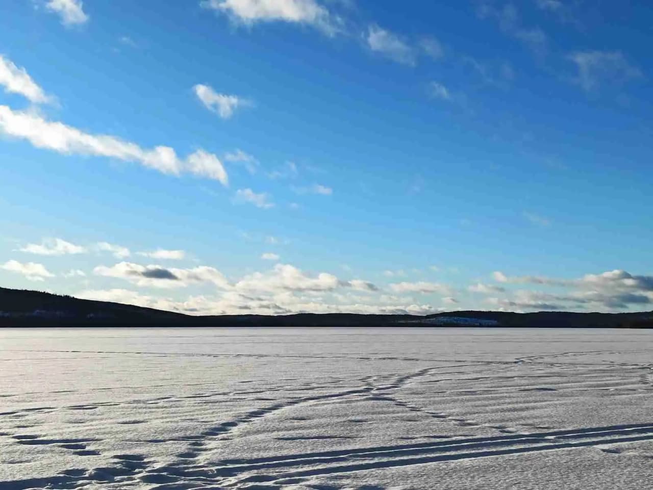 En klar, solig vinterdag vid horisonten med ett glittrande blått hav under en klarblå himmel.
