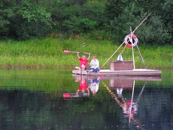 En stilla sjö med båtar förtöjda vid strandkanten, omgiven av grönska på Storängens Camping, stugor & outdoor, en plats för avkoppling och friluftsaktiviteter.