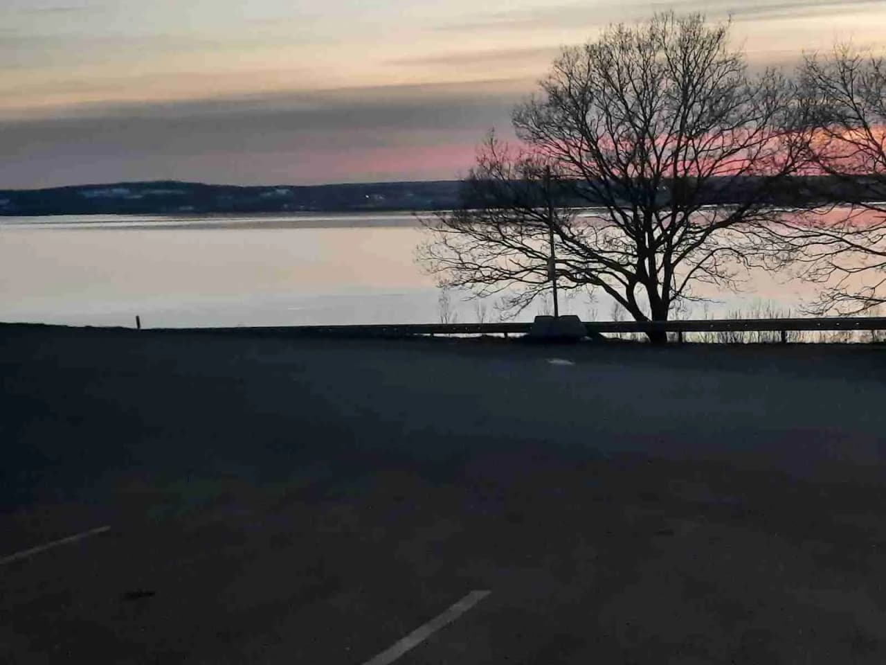 En campingplats vid Vättersmålen med asfaltvägar som leder mot horisonten. Det är skymning med solen på väg ner över kusten, vilket skapar ett varmt ljussken och en fridfull atmosfär.