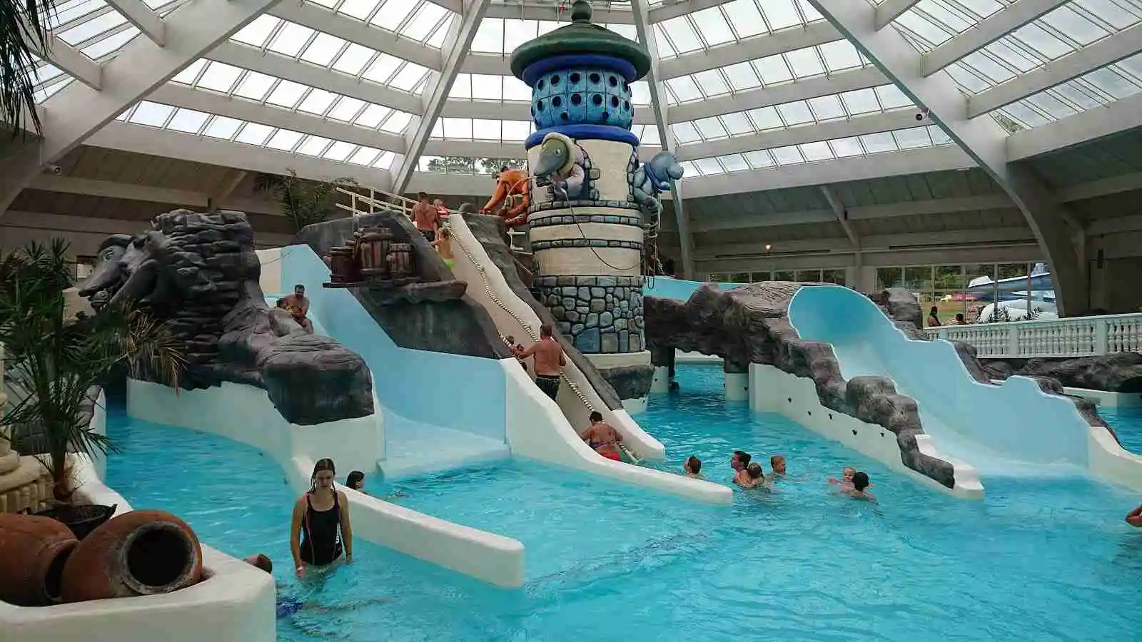 En livlig semesteranläggning med en stor pool, vattenpark och glada besökare som njuter av avkoppling och bad på Västervik Resort.