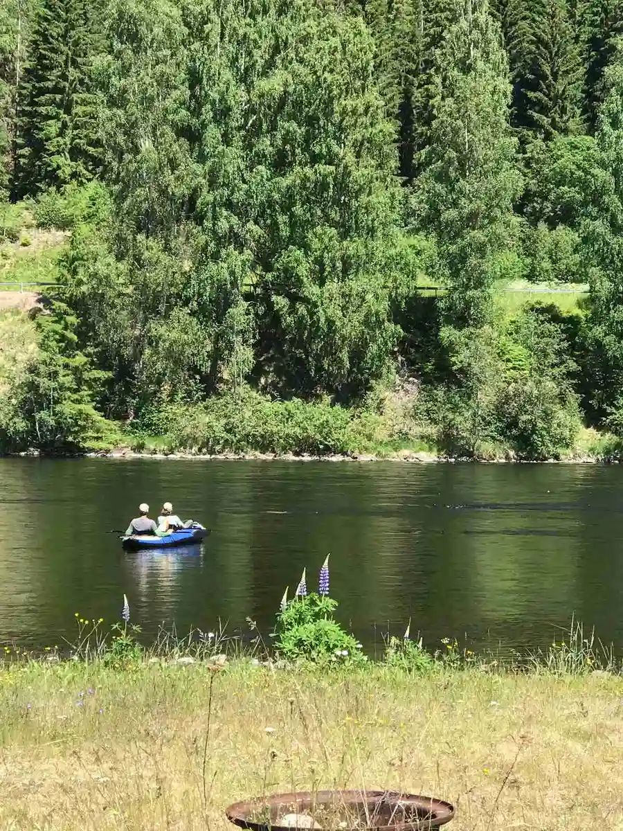 En stilla sjö med båtar vid strandkanten på Bråtens camping, omgiven av grönskande natur och en lugn atmosfär.