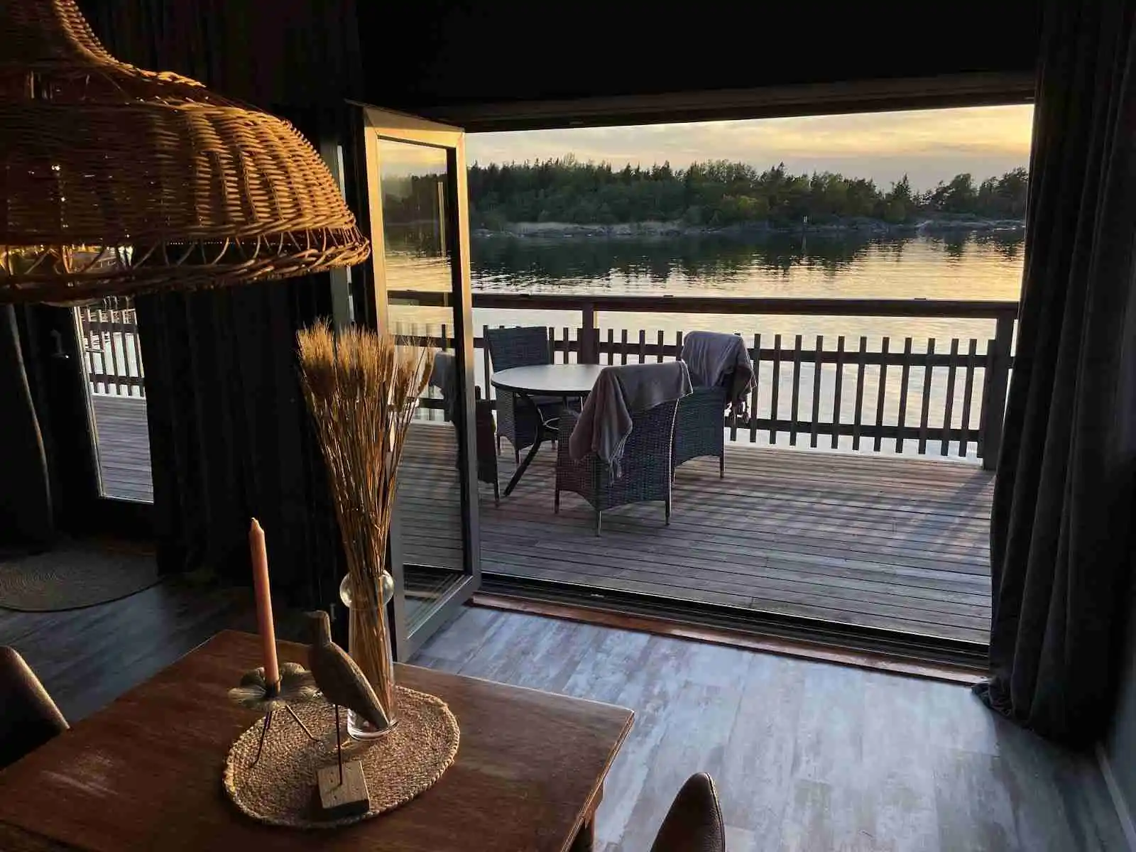 Alt-text: En träaltan med utemöbler vid kustvy & hamncampingen i Ängskär, omgiven av träplank och vacker natur.