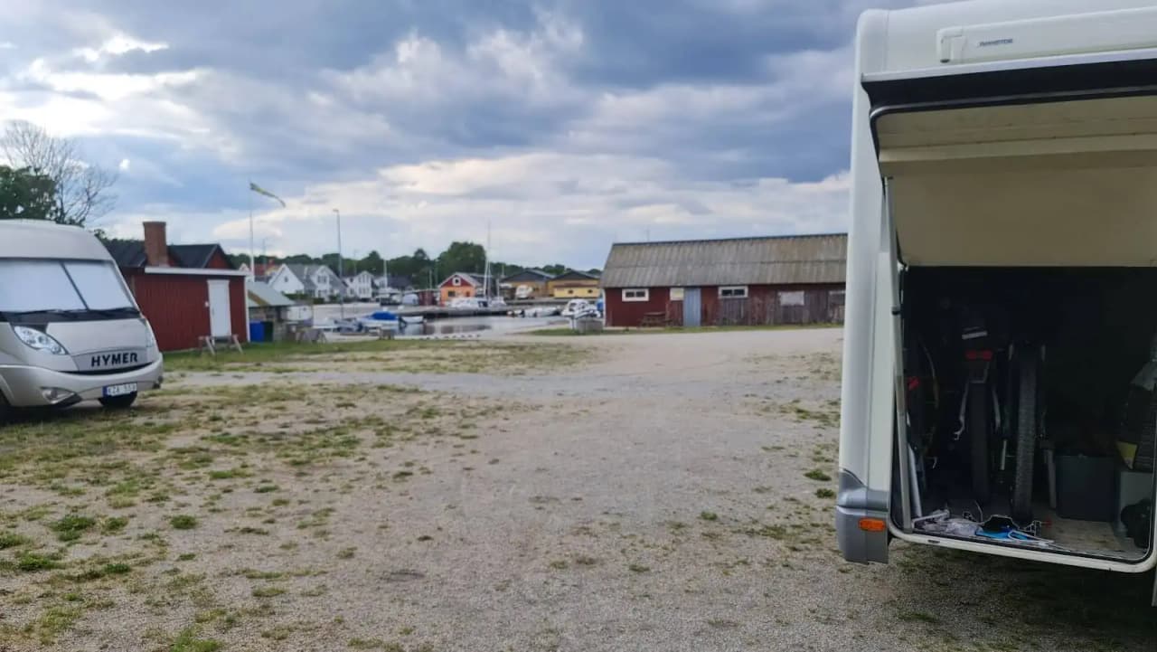 En husbil och en husvagn parkerade bredvid varandra på Valjevikens camping, omgivet av gröna träd och ett lugnt campingområde.