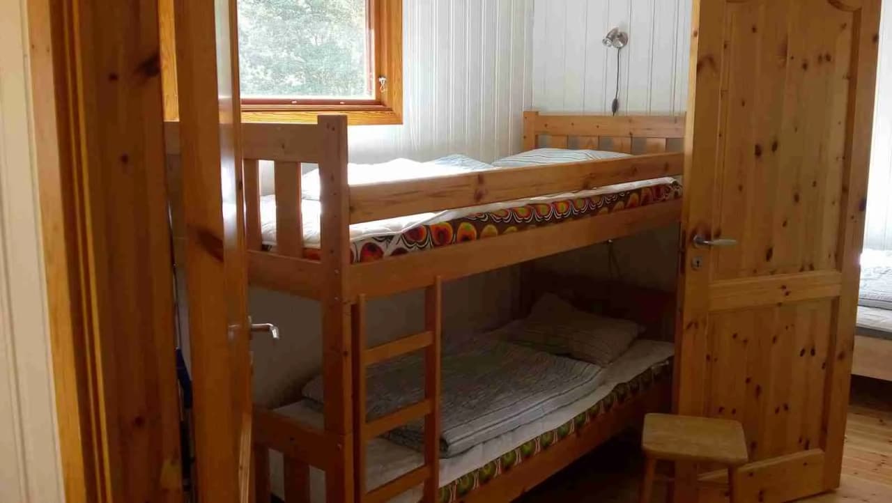 En träinredd campingstuga med våningssäng, trägolv och rustik inredning, som ger en ombonad och hemtrevlig känsla hos Haga Park Camping & Stugor.