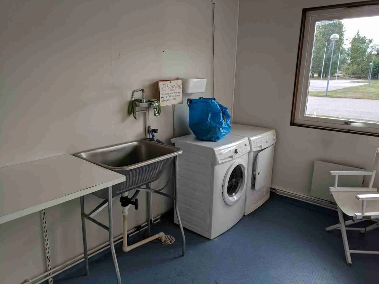 En tvättstuga på Emmaboda Camping med tvättmaskiner och torktumlare, samt klinkergolv.