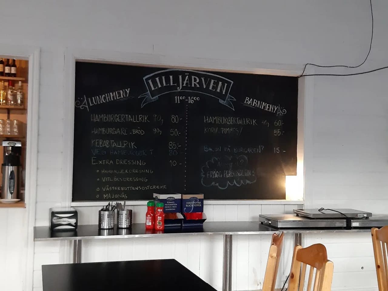 En inomhusmiljö på Storklinta Skidcenter med rustika trämöbler och en svart tavla med menyer och information om restaurangen.