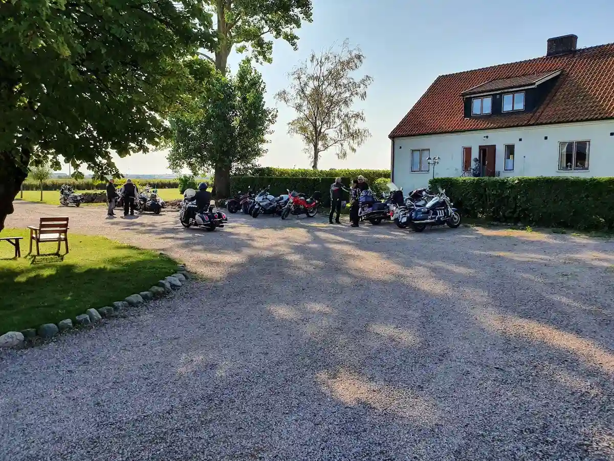 En parkering på Hanksville Farm med bilar och motorcyklar uppställda på en asfalterad uppfart under en klar himmel.