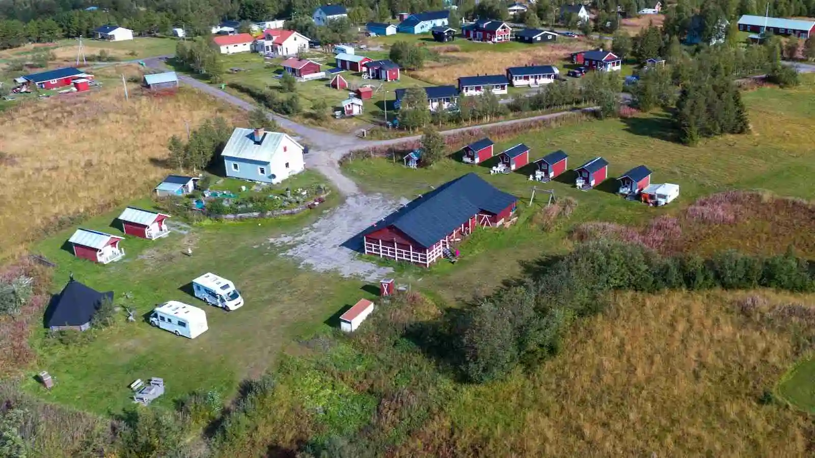 En naturskön campingplats vid Piilijärvi med en stuga belägen i ett öppet landskap, omgiven av grönska och vidsträckta fält.