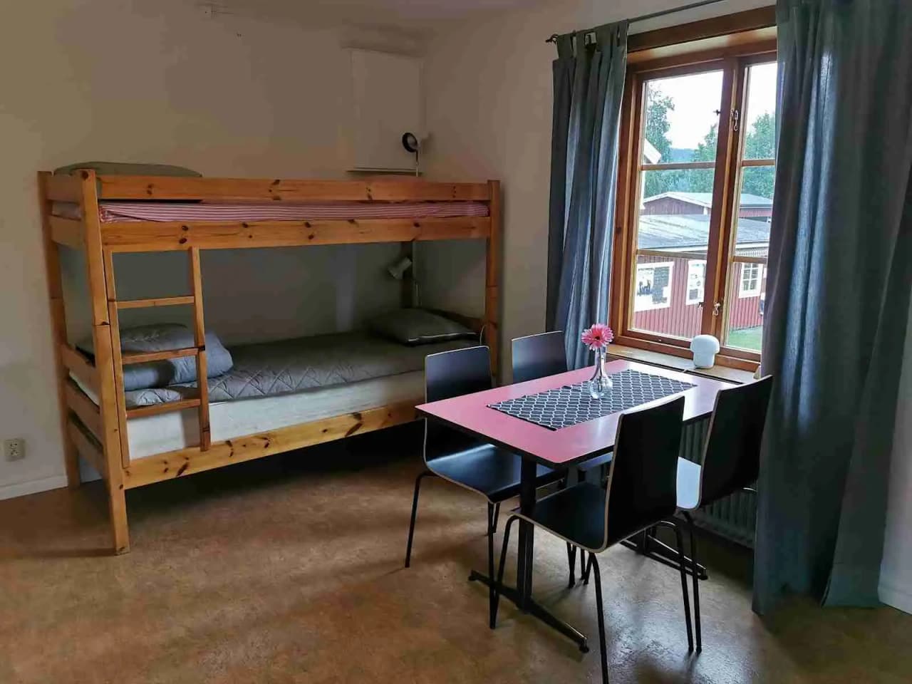 Denna bild visar ett rum med interiör på Docksta Vandrarhem & Camping Kustladan. Rummet är möblerat med en våningssäng i trä, trägolv och träpaneler på väggarna, vilket ger en rustik och mysig atmosfär.