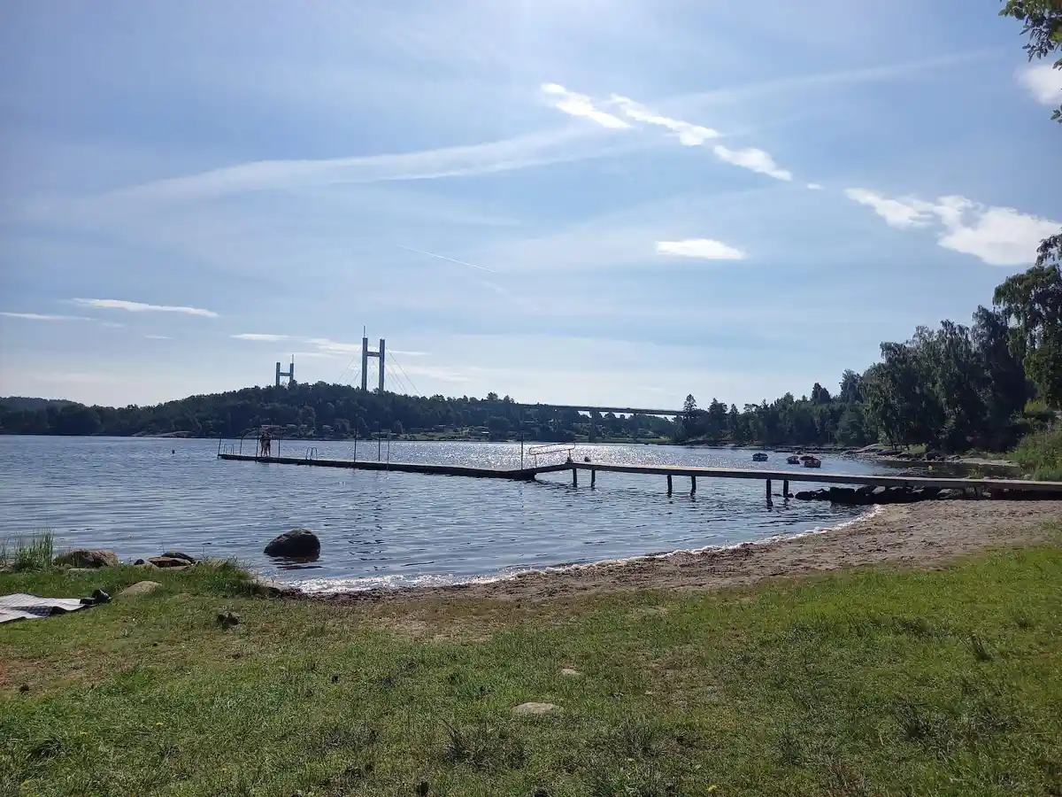 En vy över en kustlinje vid Almöns bad & camping, med vatten och strand i förgrunden.