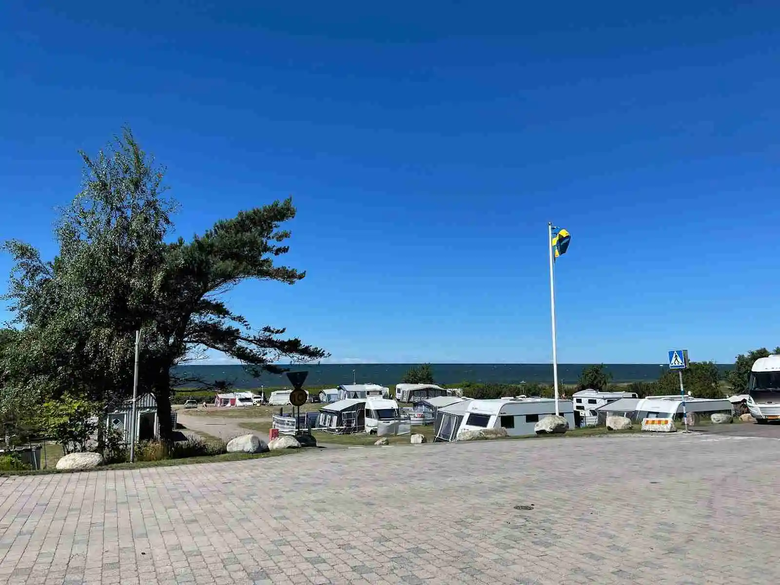 En parkering på Lerbergets camping fylld med husvagnar och husbilar, omgiven av grönska och ett lugnt landskap.