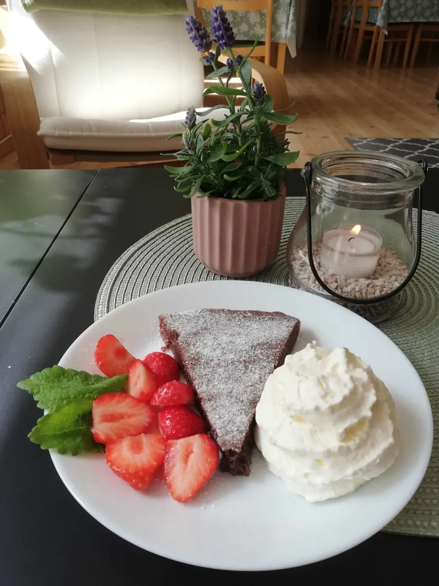 En inbjudande närbild av ett dukat bord på Stigmansgården i Tiveden, med olika fruktdesserter och kakor upplagda på elegant porslin, omgivna av bestick och serviser.