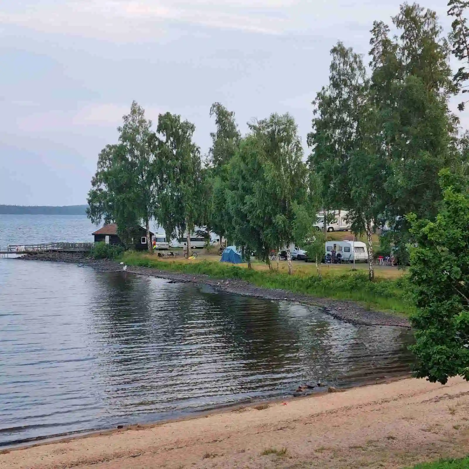 En sjö med klart vatten omgiven av grönskande natur vid Löckna camping, en populär plats för rekreation och friluftsliv.