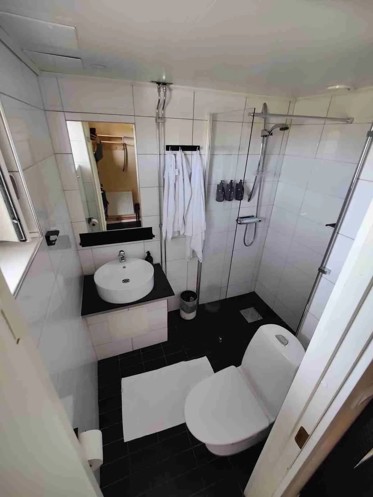 Alt-text: Ett modernt badrum på Camp Ripan med ett vitt handfat, toalettstol och snygg inredning. Golvet har ett mönstrat kakel och rummet är smakfullt designat för komfort och funktion.