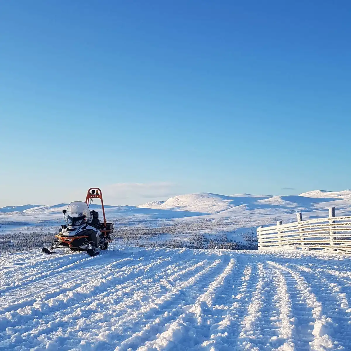 En snöklädd campingplats vid Idre Fjäll, med vinterlandskap bestående av snötäckta backar och tundra, där en snöskoter står parkerad på det frusna underlaget.