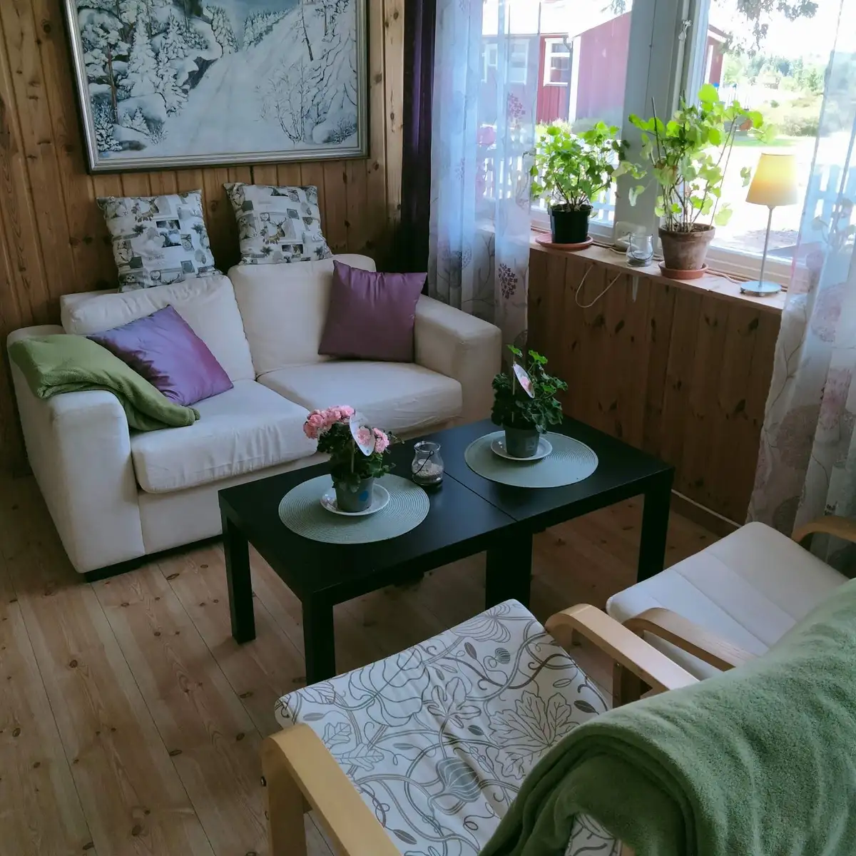 Ett mysigt vardagsrum på Stigmansgården i Tiveden med trämöbler och ett bord i centrum. Rummet har trägolv och textilier som skapar en hemtrevlig atmosfär.