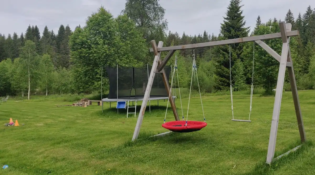 En lekplats med gungor omgiven av grönska och gräsmatta på Solberg Hults Camping.