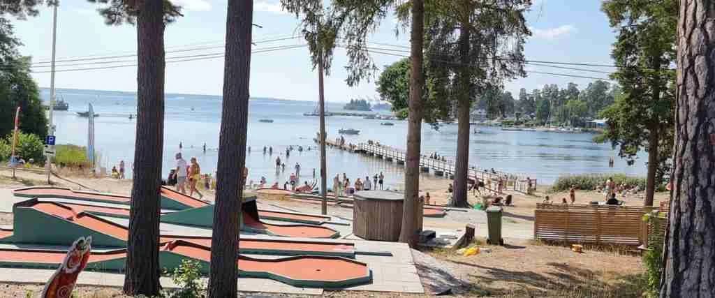 En somrig campingplats i Engesberg, Gävle med sandstrand, skuggiga områden och glada besökare som njuter av semester och fritidsaktiviteter.