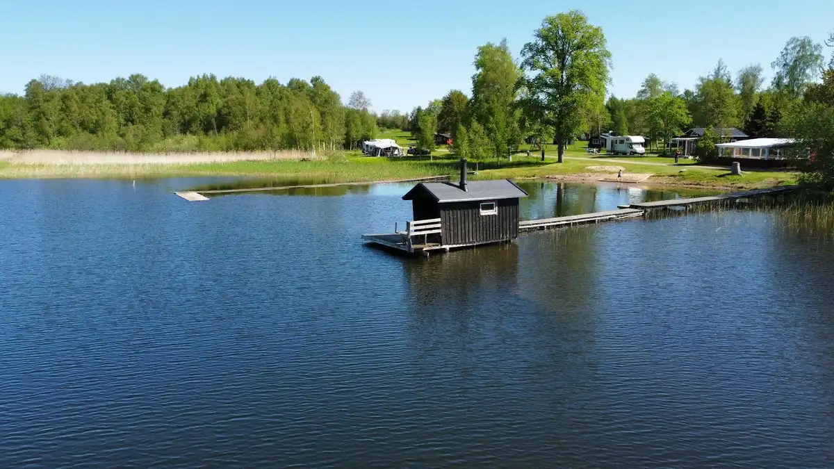 En naturskön vy över en lugn sjö omgiven av grönska, med en vattenspegel som reflekterar himlen.